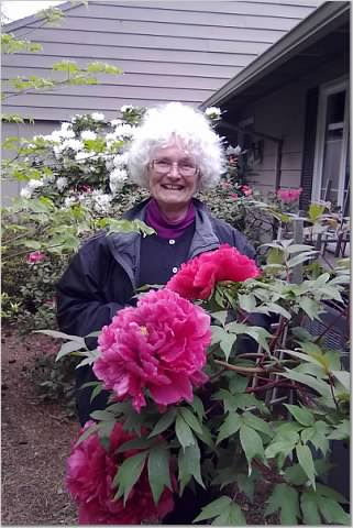 Image of Laura Coleman's client Juanita in her garden with flowering rhodedendron