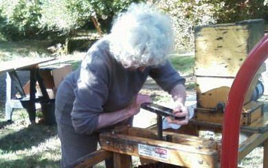 Image of an older woman using an old fashion cider press