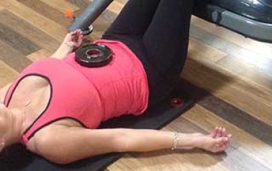 Image of woman in static back position with a weight on her stomach for breathing control
