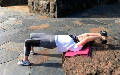 Image of woman in shoulder bridge position doing an overhead pull movement