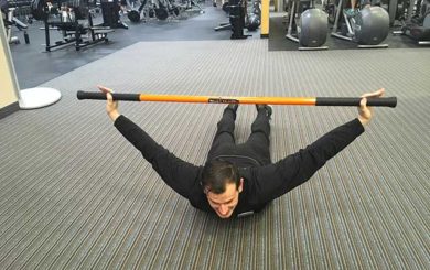 Image of man demonstrating cobra stretch exercise using a moving stick in a gym