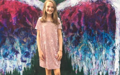 Image of young girl in front of angel wing graffiti art