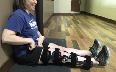 image of woman sitting against a wall with knee brace on
